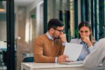 Portrait of a couple with financial problems looking at document in financial adviser's office.concept